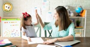 A woman homeschooling a child at a desk, emphasizing the reality of it all through a high five.