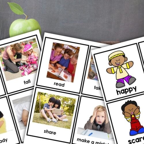 Several educational flashcards with words like "fall," "read," or "happy" are spread out on a table in front of a green apple, ideal for Social Emotional Learning or pairing with the How I Feel Emotion Sort Worksheets. Montessori Nature Printables
