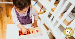 A little girl is playing with Montessori Math Tools, including a wooden box of numbers.