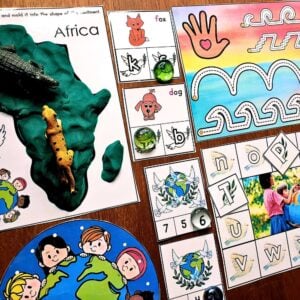 Peace Activities Play-Doh Continents Mats for children feature animal figurines on an Africa map, letter and number cards, sorting activities, and colorful worksheets, all displayed on a wooden table. Montessori Nature Printables