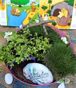 An invitation to play with a small world of plants and a book on a table, encouraging hands-on free play for children with loose parts.